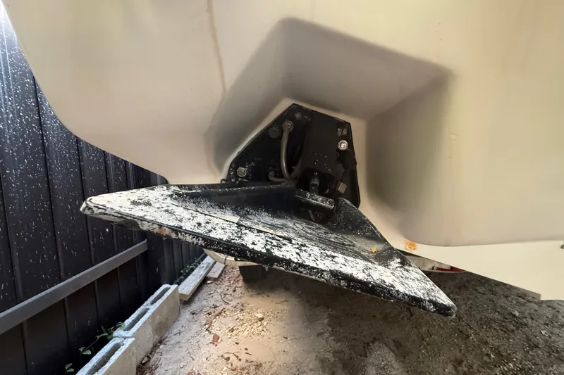 Slide: The Image of 2004 Wellcraft 32 CCF boat hull detail with trim tab, showing wear and outdoor setting. - 24