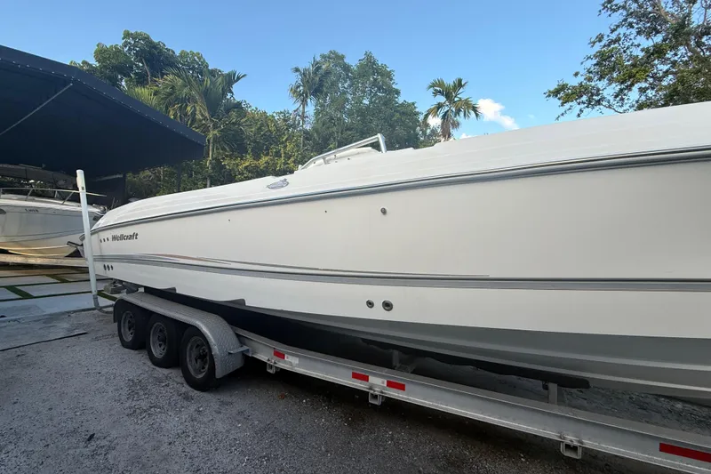 Slide: The Image of 2004 Wellcraft 32 CCF boat on trailer, surrounded by lush greenery and clear sky. - 4