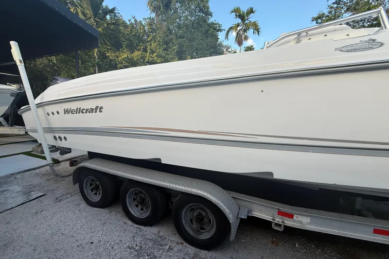 Slide: The Image of 2004 Wellcraft 32 CCF boat on trailer, surrounded by trees and parked outdoors. - 5