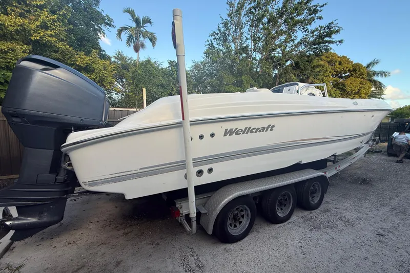 Slide: The Image of 2004 Wellcraft 32 CCF boat on trailer, parked outdoors with trees in the background. - 6