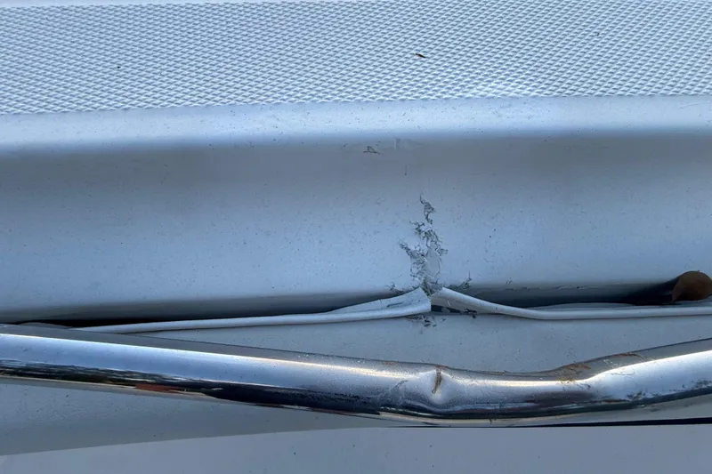 Slide: The Image of Damaged hull of 2004 Wellcraft 32 CCF boat with visible cracks and dented railing. - 65