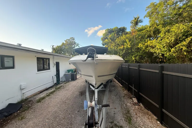 Slide: The Image of 2004 Wellcraft 32 CCF boat on trailer beside house and fence, under clear sky. - 9