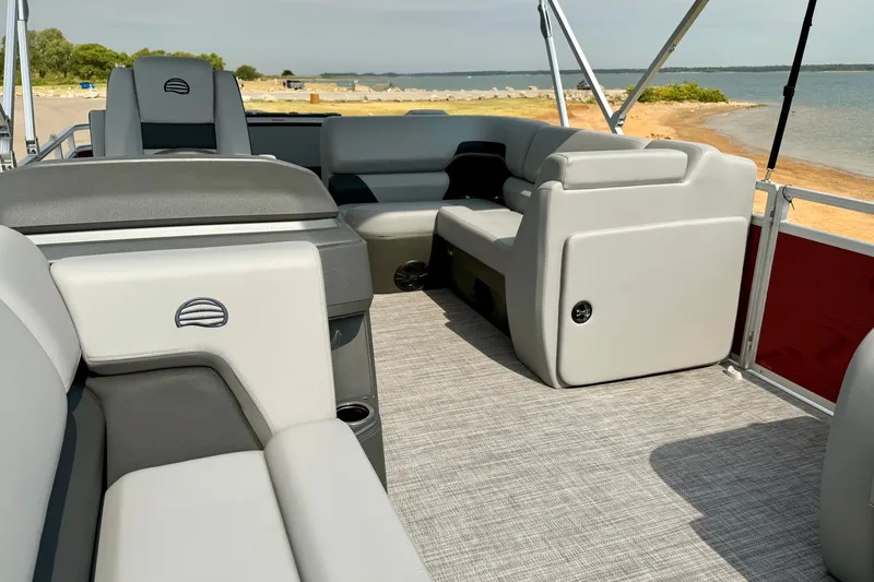 Slide: The Image of 2026 Sun Tracker SportFish 22 DLX pontoon boat interior with plush seating and lake view. - 17