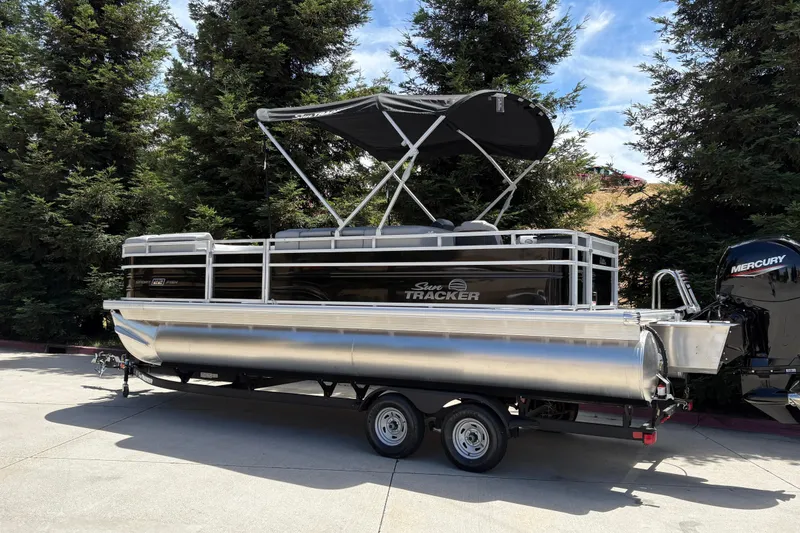 Slide: The Image of 2026 Sun Tracker SportFish 22 DLX pontoon boat with canopy, parked on trailer. - 3
