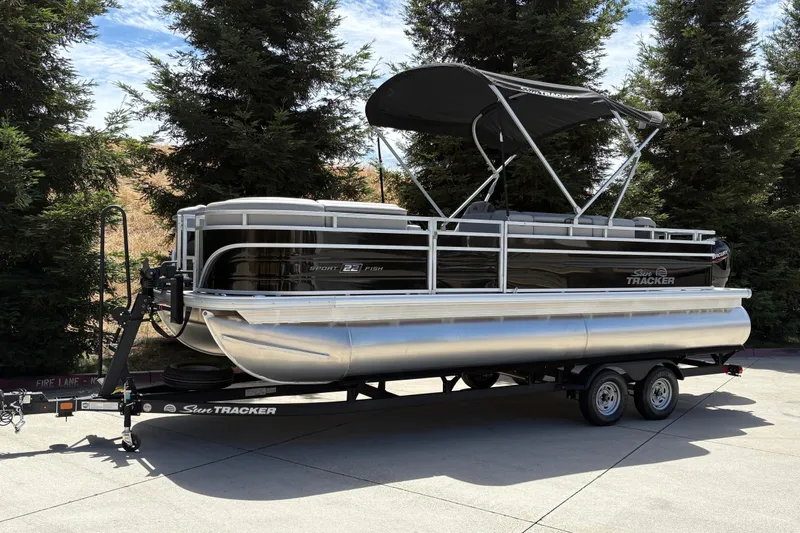 Slide: The Image of 2026 Sun Tracker SportFish 22 DLX pontoon boat on trailer, parked outdoors. - 5