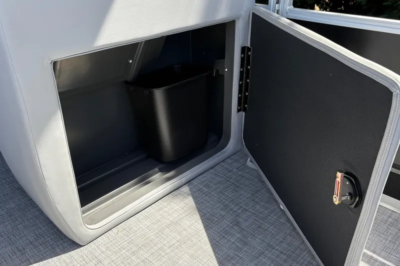 Slide: The Image of Open storage compartment on 2026 Sun Tracker SportFish 22 DLX boat with black bin inside. - 24