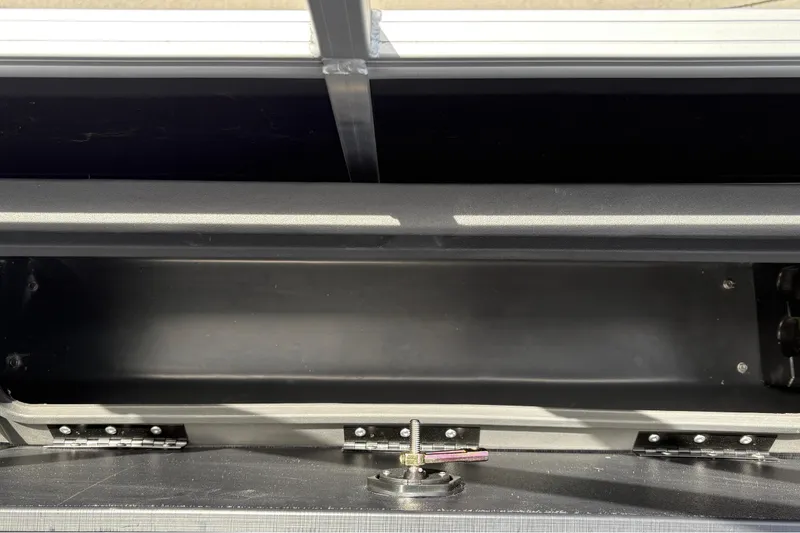 Slide: The Image of An open storage compartment on a Sun Tracker SportFish 22 DLX boat, featuring a metal latch. - 36