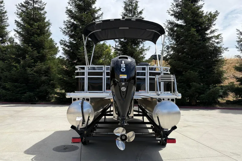 Slide: The Image of 2026 Sun Tracker SportFish 22 DLX pontoon boat with powerful outboard motor, parked outdoors. - 7