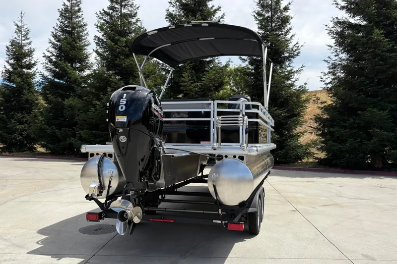 Slide: The Image of 2026 Sun Tracker SportFish 22 DLX pontoon boat with Mercury 150 engine, parked outdoors. - 6