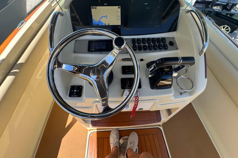 Slide: The Image of 2015 Chris-Craft Catalina 26 helm with steering wheel, navigation screen, and controls. - 11