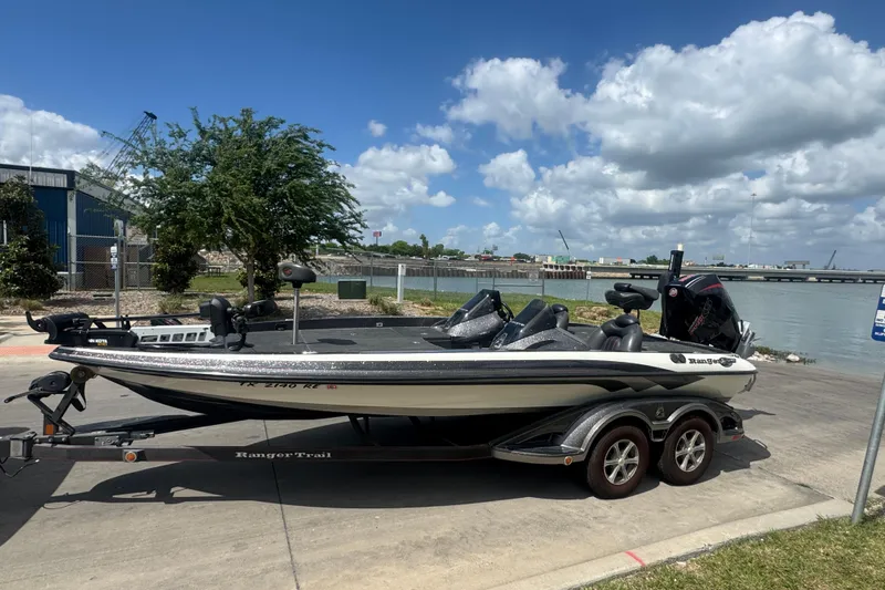 The Image of 2010 Ranger Z521 Comanche boat on trailer by waterfront, under a clear blue sky. - 0