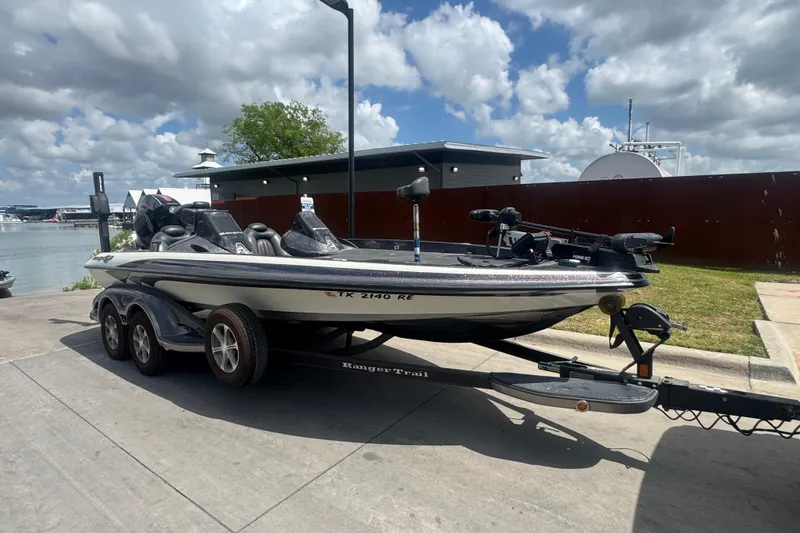 Slide: The Image of 2010 Ranger Z521 Comanche boat on trailer, parked near waterfront under cloudy sky. - 2