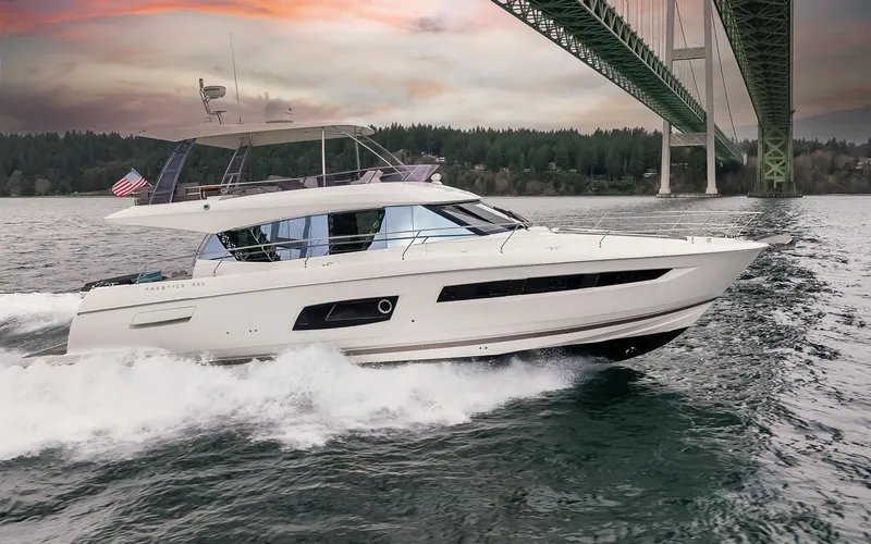 Slide: The Image of 2017 Prestige 560 yacht cruising on open water, surrounded by lush greenery. - 2