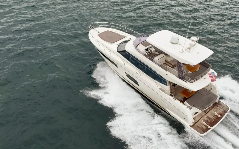Slide: The Image of 2017 Prestige 560 yacht cruising on a scenic lake with forested shoreline. - 6