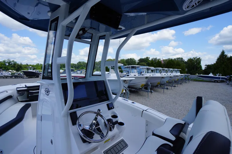 Slide: The Image of 2026 Tidewater 232 LXF boat interior with steering wheel, parked among other boats. - 63