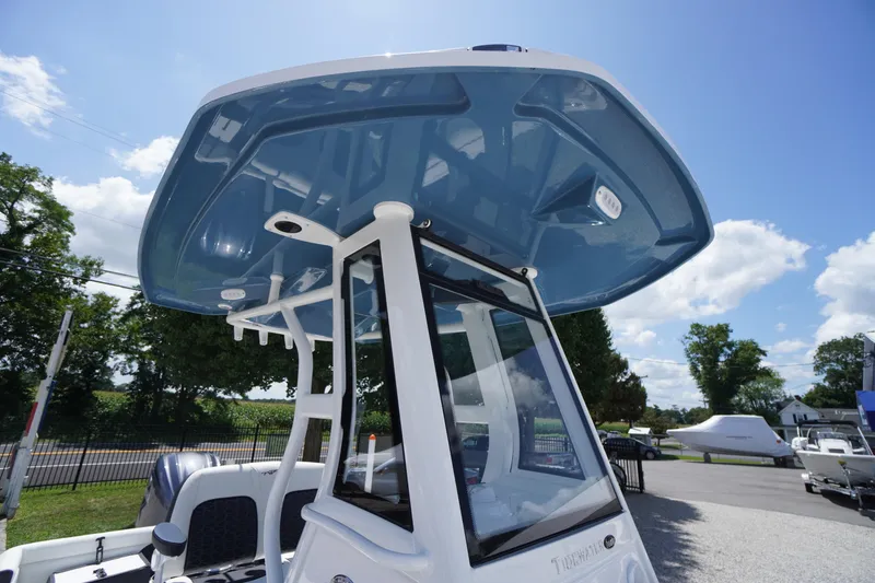 Slide: The Image of 2026 Tidewater 232 LXF boat with blue T-top, parked outdoors under a clear sky. - 64