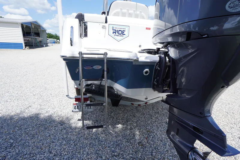 Slide: The Image of 2026 Tidewater 232 LXF boat rear view with ladder and engine, parked on gravel. - 74