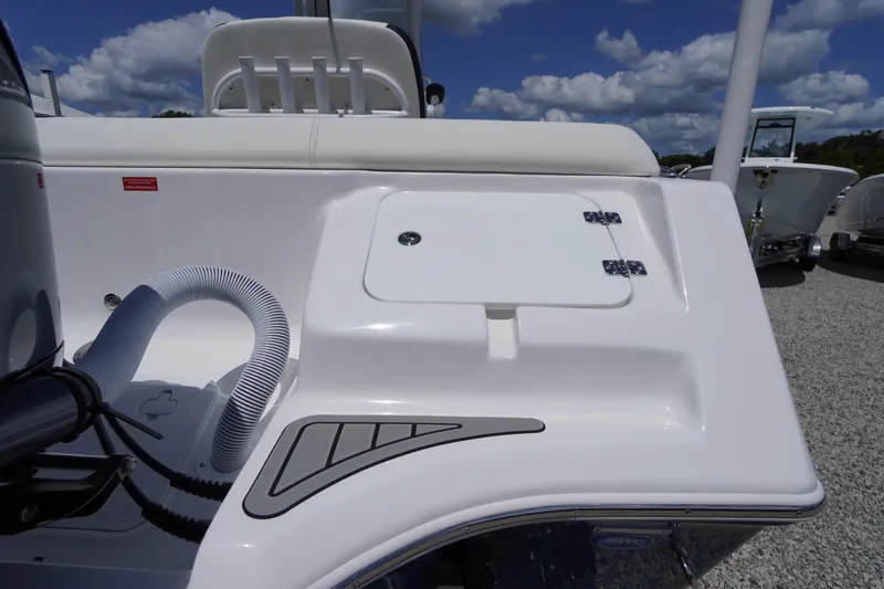 Slide: The Image of 2026 Tidewater 232 LXF boat deck with storage compartment and hose, under a blue sky. - 75