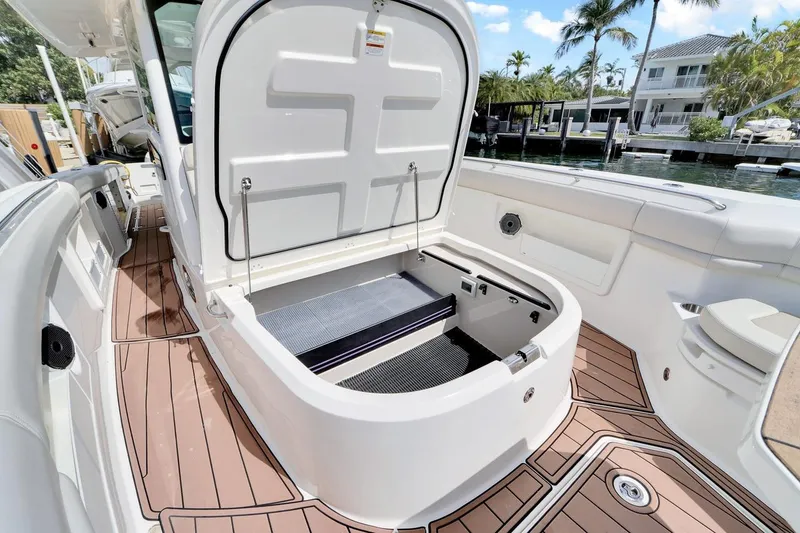Slide: The Image of 2020 Boston Whaler 380 Outrage boat interior with open storage compartment, docked by waterfront homes. - 18