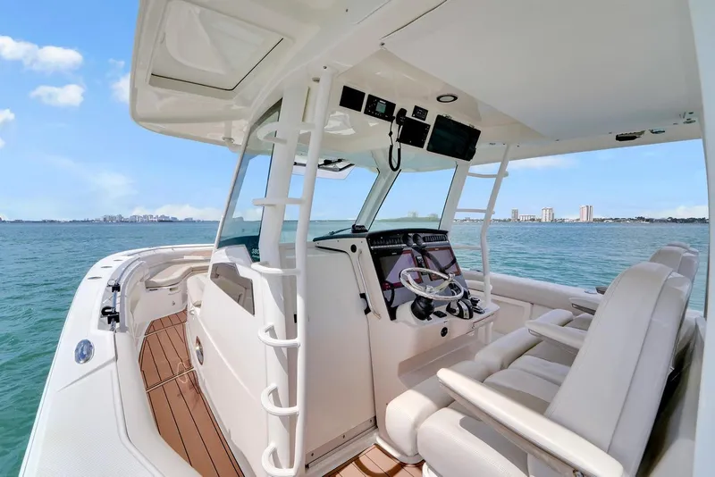 Slide: The Image of 2020 Boston Whaler 380 Outrage boat interior with helm, ocean view, and city skyline. - 37