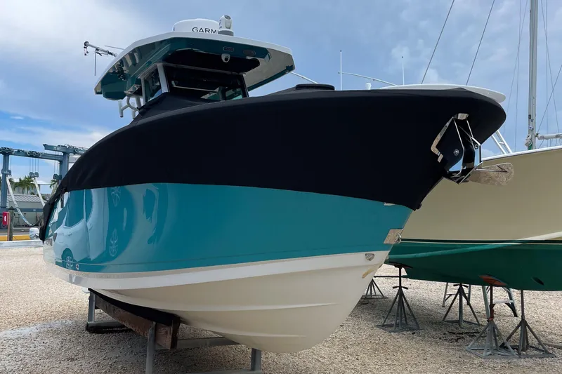 Slide: The Image of 2021 Blackfin 272 CC boat with black cover, displayed on stands. - 10