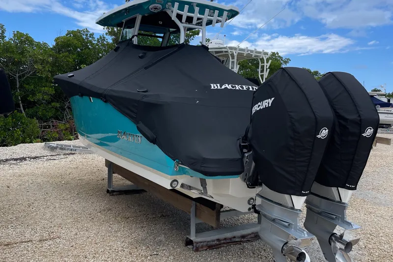 Slide: The Image of 2021 Blackfin 272 CC boat with dual Mercury engines, covered and docked outdoors. - 12
