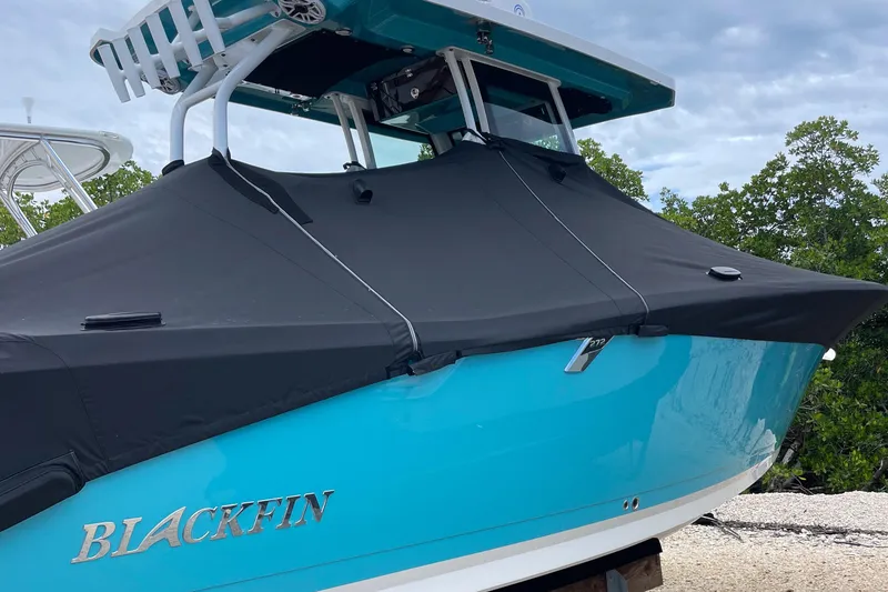 Slide: The Image of 2021 Blackfin 272 CC boat with black cover, turquoise hull, and sleek design. - 13