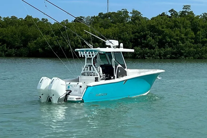 Slide: The Image of 2021 Blackfin 272 CC boat on calm water, surrounded by lush greenery. - 4