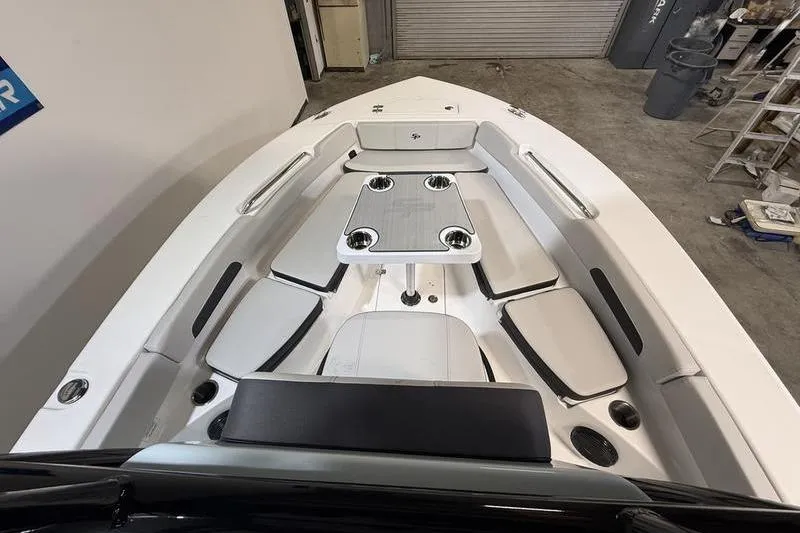 Slide: The Image of 2026 Sea Pro 202 Center Console boat interior with seating and table in a garage setting. - 29