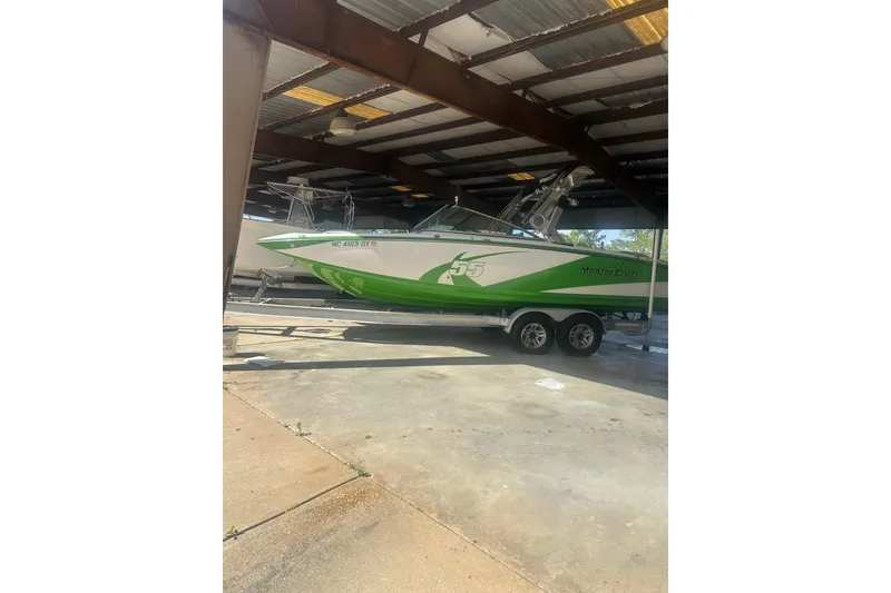 Slide: The Image of 2013 MasterCraft X55 boat in storage, green and white design on trailer. - 11
