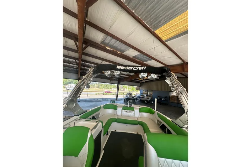 Slide: The Image of 2013 MasterCraft X55 boat with green and white seating, under a metal roof. - 3