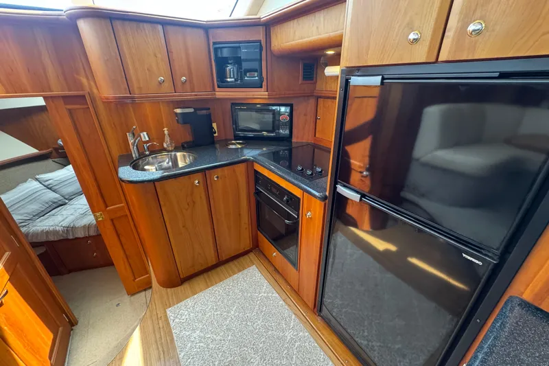 Slide: The Image of Luxurious 2003 Silverton 39 Motor Yacht kitchen with wood cabinetry and modern appliances. - 27