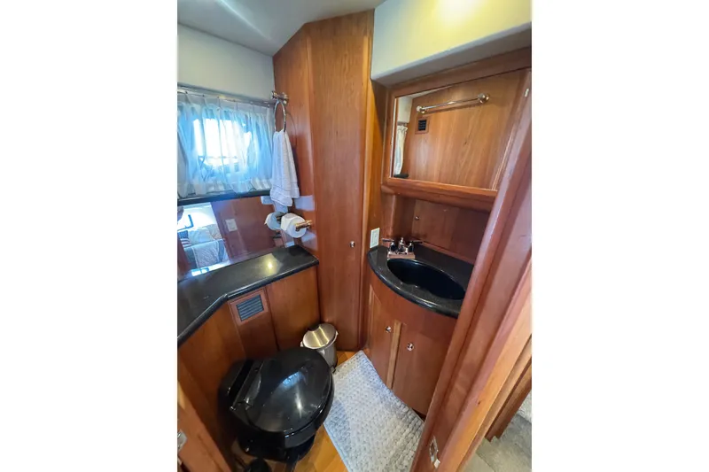 Slide: The Image of 2003 Silverton 39 Motor Yacht bathroom with wood cabinetry and black fixtures. - 34