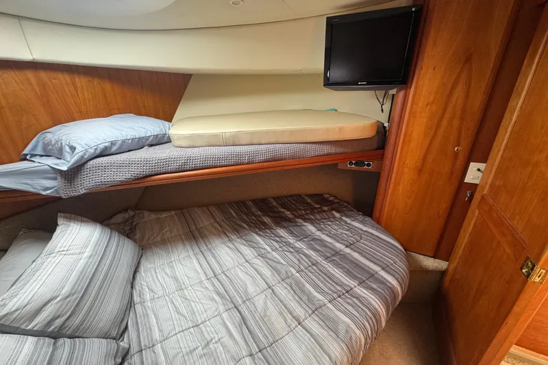Slide: The Image of 2003 Silverton 39 Motor Yacht cabin with bunk beds and wall-mounted TV. - 39