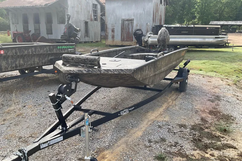 Slide: The Image of 2026 Excel Eclipse 1754 boat on trailer, parked outdoors near rustic buildings. - 2