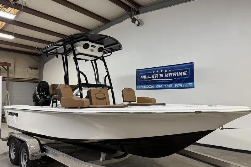 Slide: The Image of 2026 Sea Pro 210 Bay boat on trailer in showroom, Miller's Marine banner visible. - 3