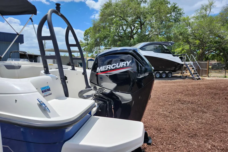 Slide: The Image of 2021 Bayliner Element E18 with Mercury outboard motor, parked outdoors under a clear sky. - 10