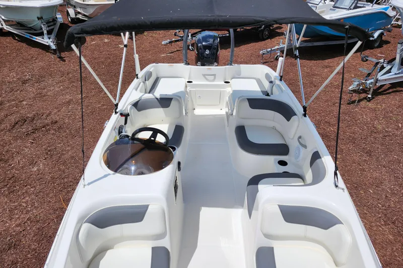 Slide: The Image of 2021 Bayliner Element E18 boat interior with seating and canopy, displayed outdoors. - 21