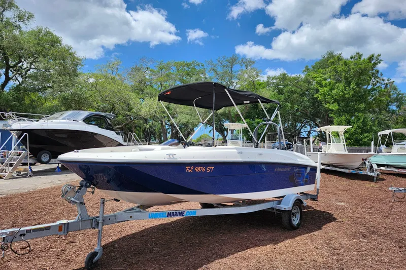 Slide: The Image of 2021 Bayliner Element E18 boat on trailer, parked outdoors under a blue sky. - 3