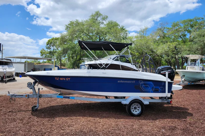 Slide: The Image of 2021 Bayliner Element E18 boat on trailer, parked outdoors under a cloudy sky. - 4