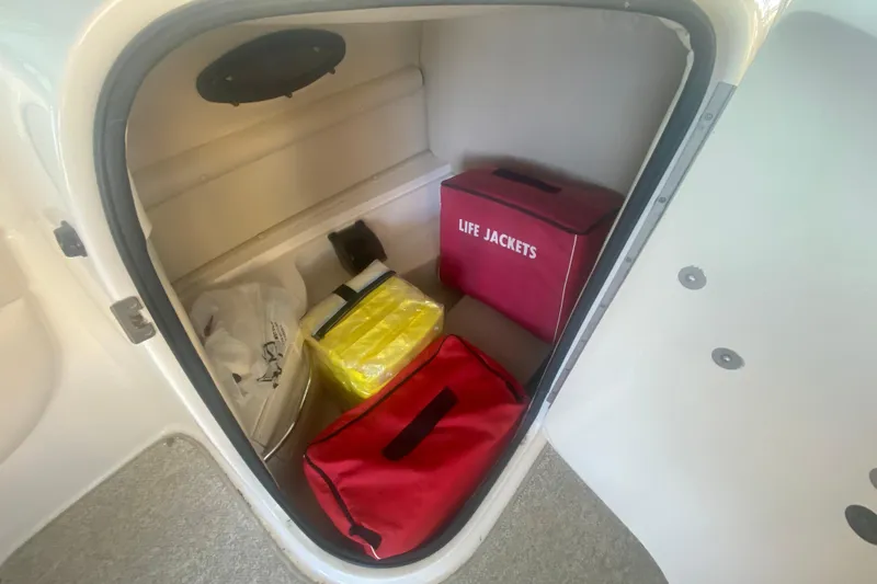 Slide: The Image of Storage compartment in a 2003 Chaparral Sunesta 263 with life jackets and safety gear. - 13