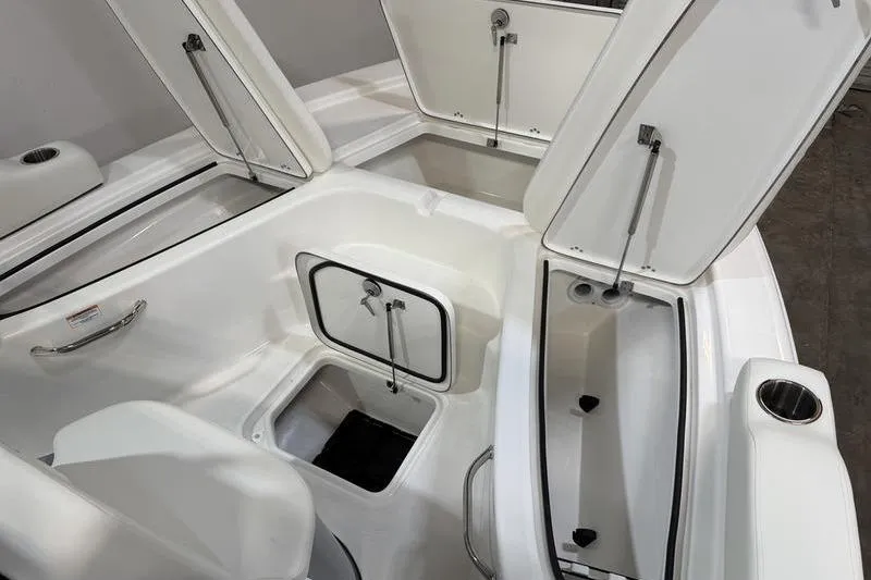 Slide: The Image of 2026 Sea Pro 210 Bay boat interior with open storage compartments and cup holder. - 21