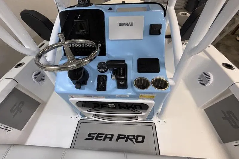 Slide: The Image of 2026 Sea Pro 210 Bay boat console with steering wheel, Simrad display, and cup holders. - 12