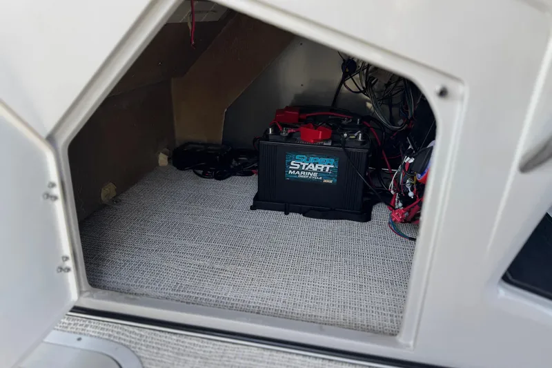 Slide: The Image of 2023 SunCatcher Elite 326 SE boat battery compartment with marine battery and wiring. - 29
