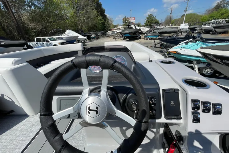 Slide: The Image of 2026 Harris Cruiser 230 SLDH boat dashboard with steering wheel and controls in a marina setting. - 7