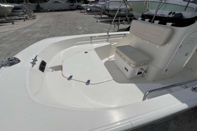 Slide: The Image of 2023 Boston Whaler 150 Montauk boat interior with seating and storage, parked in a marina. - 12