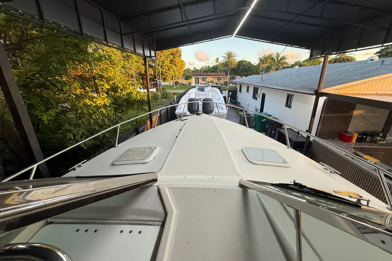 Slide: The Image of 2005 Formula 330 Sun Sport boat docked under a canopy, surrounded by trees and buildings. - 31