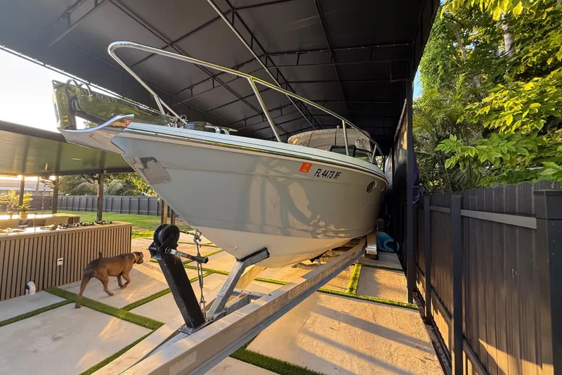 Slide: The Image of 2005 Formula 330 Sun Sport boat on trailer under shelter, with a dog nearby. - 6