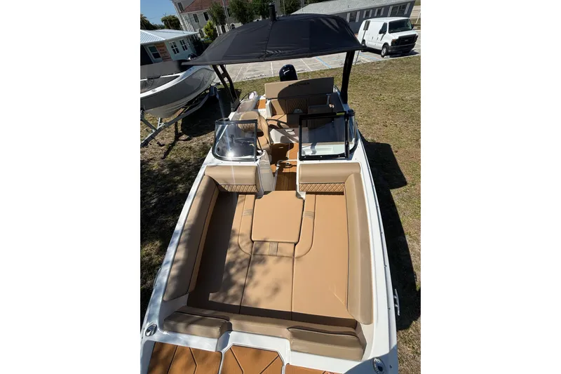 Slide: The Image of 2026 Bayliner D20 boat with tan seating and black canopy, parked on grass. - 11