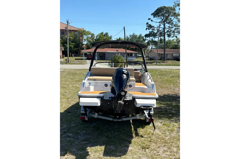 Slide: The Image of 2026 Bayliner D20 boat with outboard motor, parked on grass under clear sky. - 2